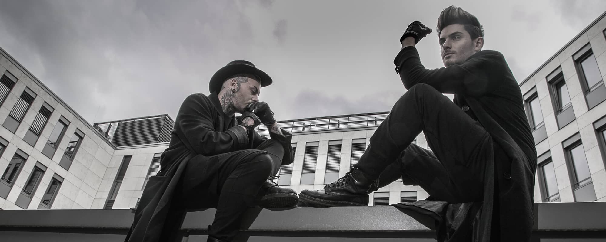 Zwei Männer in schwarzer Kleidung vor einem modernen Gebäude
