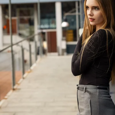 Frau mit langen blonden Haaren lehnt an einer Wand und schaut zur Seite - Natürliches Porträt mit weichem Licht