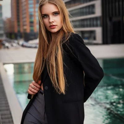 Model Anastasiia Bondarchuk in schwarzem Blazer steht auf dem Glasboden vor dem Teich am Hyatt Regency Düsseldorf oberhalb der Treppe – moderne Architektur im Hintergrund