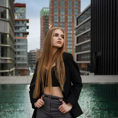 Model Anastasiia Bondarchuk trägt bauchfreie schwarze Korsage und schwarzen Blazer steht vor einem Wasserbecken im Medienhafen Düsseldorf bei einem urbanen Shooting