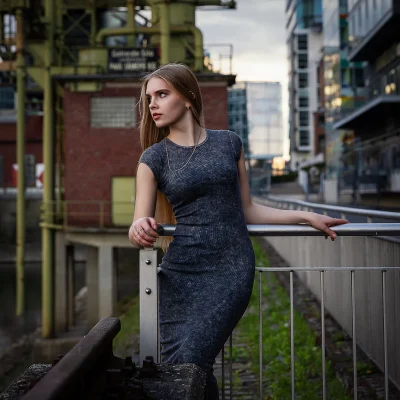 Model im enganliegenden Kleid am Geländer vor Industriearchitektur im Medienhafen Düsseldorf