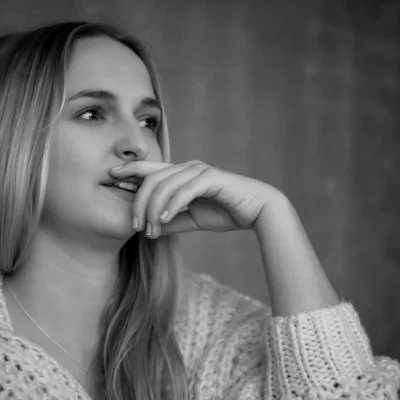 Weibliches Model mit langem Haar in einem Indoor-Porträt, nachdenklich mit Hand halb vor dem Mund