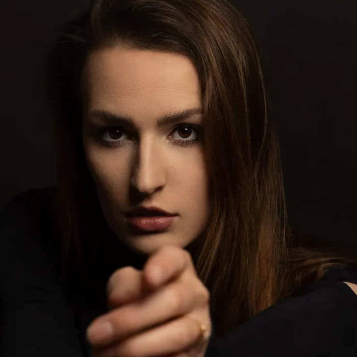 Low-Key Portrait eines weiblichen Models mit langem Haar, das mit ernster Miene direkt in die Kamera zeigt.