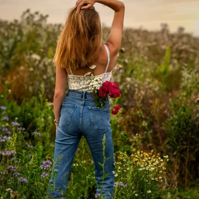 Frau mit Blumen in der Tasche vor Feld