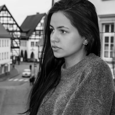 Portrait eines weiblichen Models mit langen Haaren in einem grauen Pullover vor Fachwerkhäusern