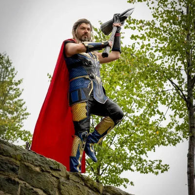 Kyurocosplay in Thor-Cosplay mit rotem Umhang und erhobenem Hammer steht auf der Stadtmauer in Soest