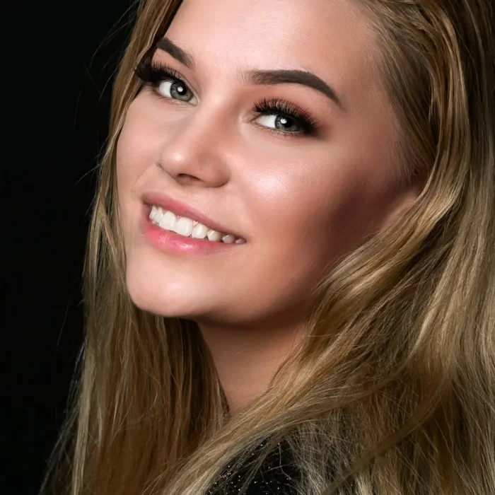 Weibliches Model mit langen blonden Haaren, das lächelnd über die Schulter schaut