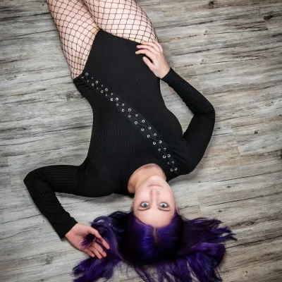 Frau mit lila Haaren liegt auf Boden
