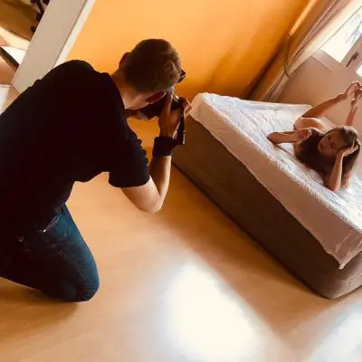 Fotograf macht ein Bild von Model auf Bett