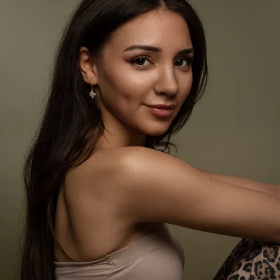 Portraitfotografie eines weiblichen Models mit langen dunklen Haaren, das in seitlicher Position lächelnd zur Kamera schaut