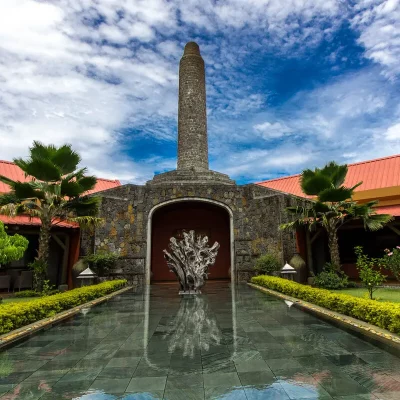 Chamarel Rum-Destillerie auf Mauritius mit Wasserbecken und markanter Statue vor dem Eingang, umgeben von tropischen Pflanzen