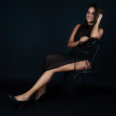 Frau in schönem Kleid mit langem Beinschlitz auf einem Stuhl