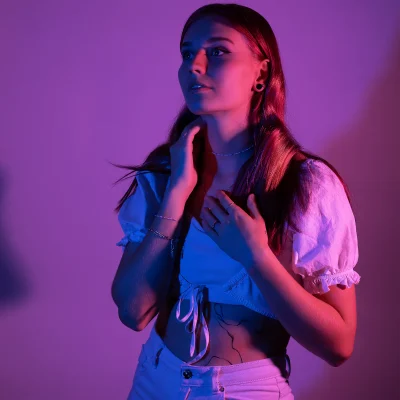 Portraitfotografie eines weiblichen Models mit langen Haaren, weiß gekleidet, dramatisch in rosa und blauer Lichtstimmung beleuchtet
