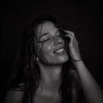 Frau mit nassen, langen Haaren, die eine Hand an den Kopf hält, vor schwarzem Hintergrund - Fotoshooting im Fotostudio in Soest