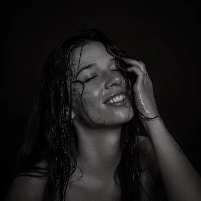 Frau mit nassen, langen Haaren, die eine Hand an den Kopf hält, vor schwarzem Hintergrund - Fotoshooting im Fotostudio in Soest