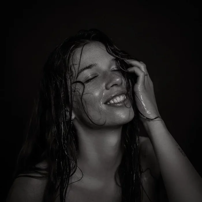 Frau mit nassen, langen Haaren, die eine Hand an den Kopf hält, vor schwarzem Hintergrund - Fotoshooting im Fotostudio in Soest