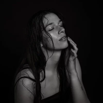 Schwarz-weiße Aufnahme von Julia mit nassen, langen Haaren, die den Kopf leicht nach hinten neigt und eine Hand an die Wange legt