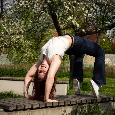 Junge Frau macht eine Brücke auf einer Holzbank im Park in Soest