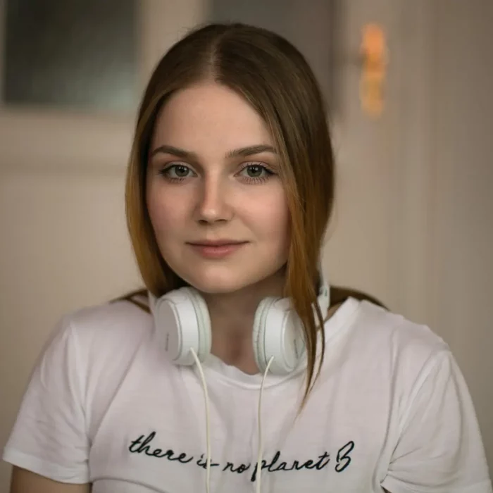 Junge Frau mit weißen Kopfhörern um den Hals und weißem T-Shirt mit dem Text „there is no planet B“