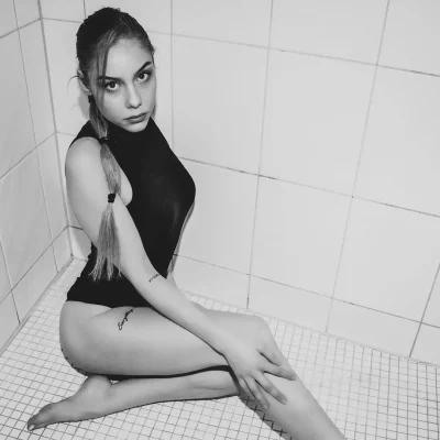Frau in schwarzem Body sitzt in einer Dusche