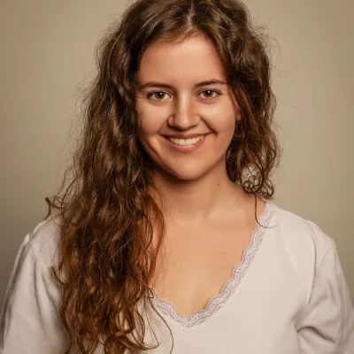 Model im weißen V-Shirt mit Spitzenkante lächelt breit vor beigem Hintergrund – Portraitfotografie Soest