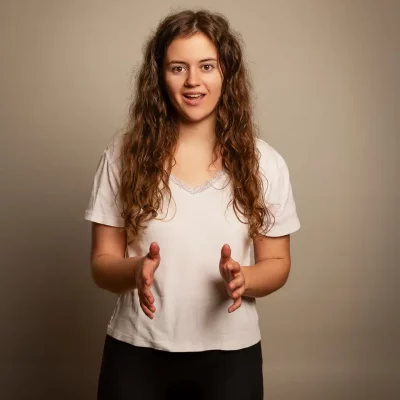 Lena steht vor beigem Studiohintergrund, gestikuliert mit beiden Händen und singt – TFP-Portrait im Studio Soest