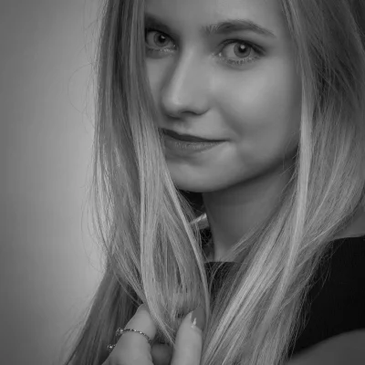 Schwarz-weißes Porträt eines weiblichen Models mit langen, offenen Haaren, Blick über die Schulter und dezentem Lächeln