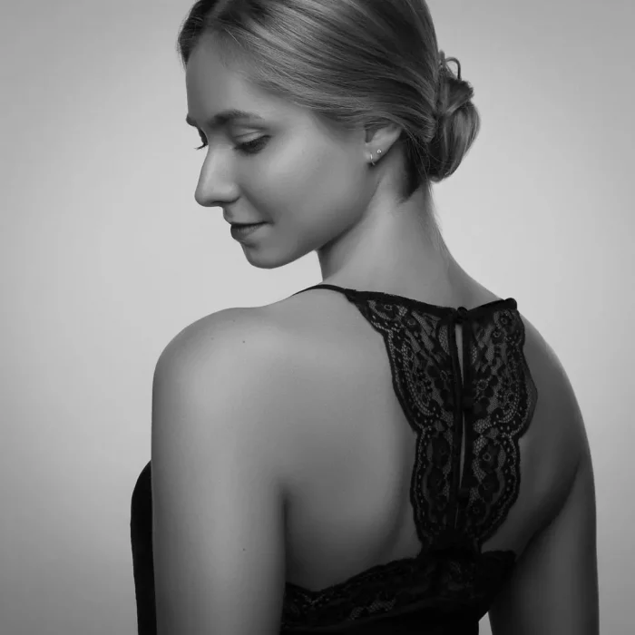 Portraitfotografie mit weiblichem Model im schwarzen schulterfreien Oberteil, das über die Schulter blickt
