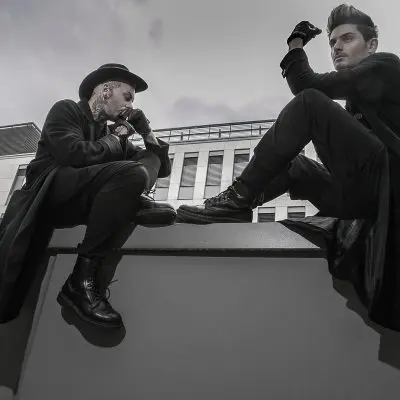 Zwei Männer in schwarzer Kleidung sitzend von unten fotografiert