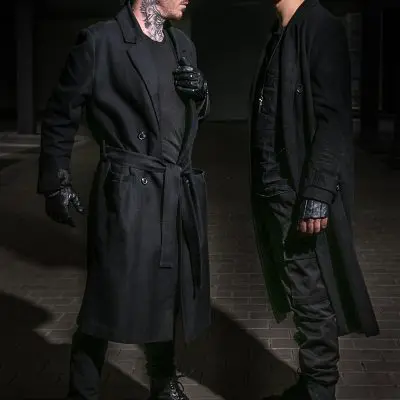 Zwei Männer in schwarzer Kleidung vor dunklem Hintergrund