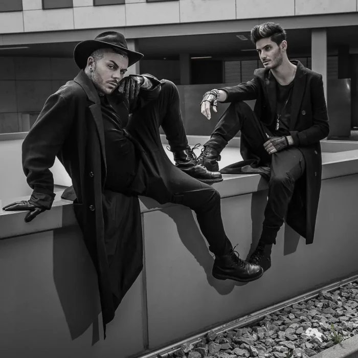 Portrait Fotoshooting Dortmund: Zwei Männer in schwarzer Kleidung posieren auf einer Mauer, ein Model mit Hut und markantem Gesichtsausdruck.