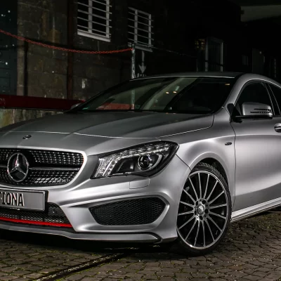 Silberner Mercedes CLA auf Kopfsteinpflaster bei Nacht, Autofotografie mit beleuchteter Fahrzeugfront