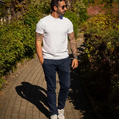 TFP-Outdoor-Shooting mit Nevio im weißen T-Shirt und Sonnenbrille auf einem begrünten Weg vor der Stadthalle in Soest im Abendlicht.