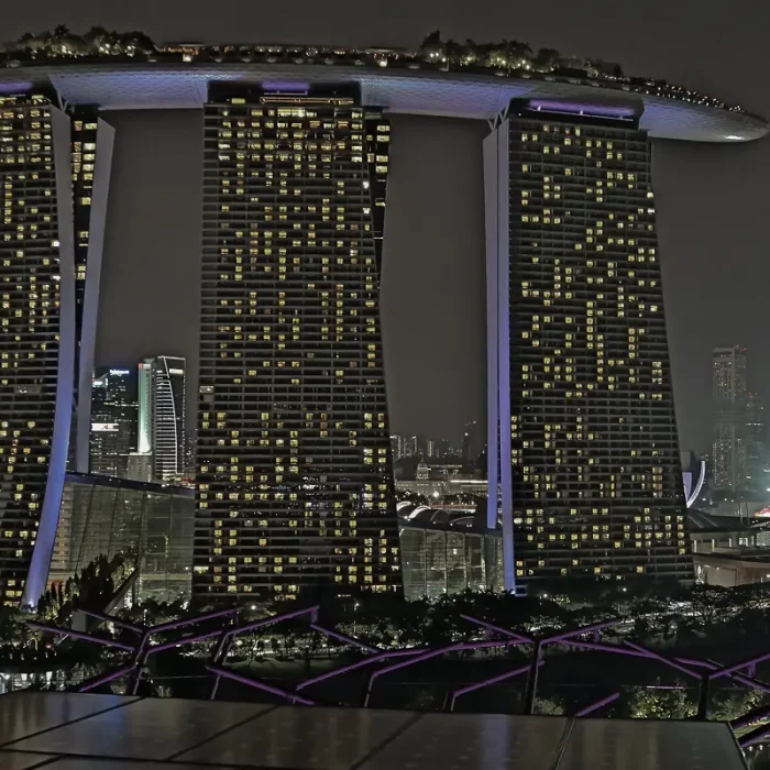 Nachtaufnahme des Marina-Bay-Sands-Hotels in Singapur mit beleuchteten Fenstern und dem charakteristischen Dach in futuristischer Architektur