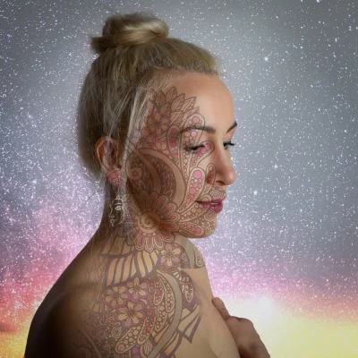 Porträtfotografie eines weiblichen Models mit floralem Ornament als Lichtprojektion auf Gesicht und Oberkörper vor funkelndem Hintergrund