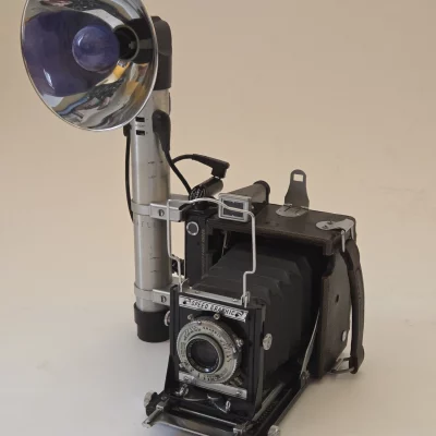 Vintage Graflex Speed Graphic 3x4-Zoll Kamera mit Ektar 4.5/101mm Objektiv und montiertem Reflektor-Blitz auf weißem Hintergrund